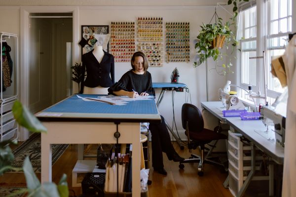Photo of Myriam Marcela sketching at sewing table 