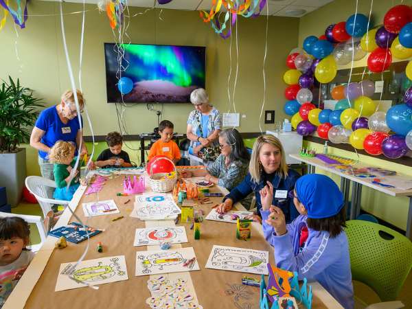 adults and children sitting at a table coloring